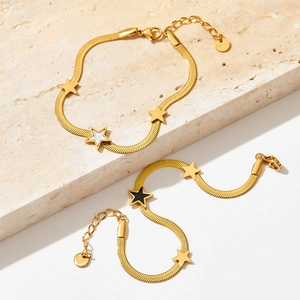 Golden stainless steel snake chain bracelet set with star pendants on a stone slab