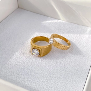Macro shot of gold couple rings with gear texture and luxury square gemstone in jewelry box