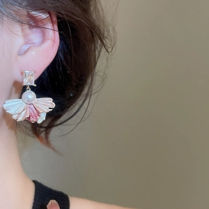 Detailed close-up of zircon and pearl drop earrings with pink petal charm worn by model