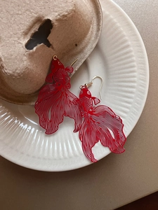 Detailed close-up of red koi fish drop earrings with hollow metal texture and golden hooks
