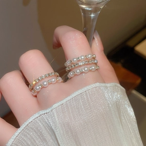 Close-up of elegant multilayer gold ring with pearls and zircons on a finger