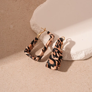 Detail of leopard print faux leather geometric earrings with gold posts on stone
