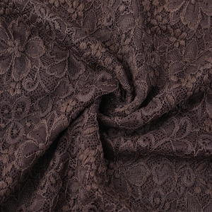 Macro detail of dark brown lace fabric featuring intricate floral embroidery and texture