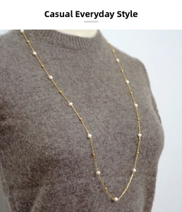 Détail d'un long collier de perles d'eau douce sur un pull marron pour un style élégant