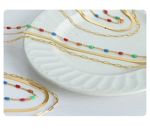 Détail d'un collier triple couche en acier titane doré avec des perles colorées