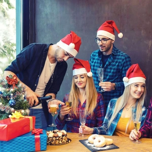 Festive group wearing red Christmas hats celebrating with gifts and party decor
