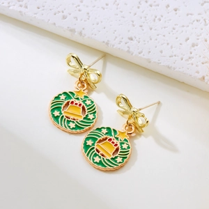 Detail of Christmas wreath earrings with golden bow, green leaves and red enamel accents
