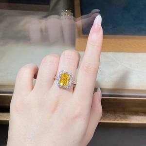 Macro shot of rectangular yellow zircon ring with silver halo and pavé band