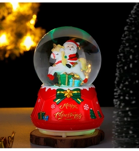 Close-up of a festive Christmas crystal ball with Santa on a unicorn and red base