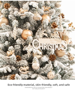 Détail d'un panneau Joyeux Noël doré sur un sapin enneigé avec des pommes de pin