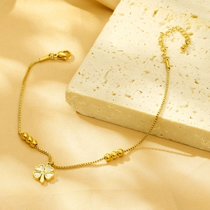 Elegant gold titanium steel clover bracelet with white shell inlays on silk background
