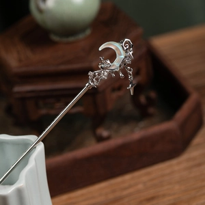Detailed close-up of moon and star hair stick with flowing silver tassels and stones