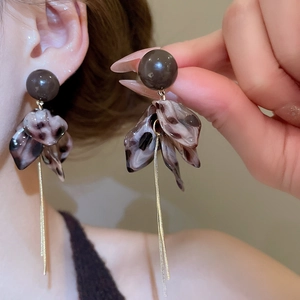 Détail de boucles d'oreilles rétro en écaille avec franges de chaînes dorées sur modèle
