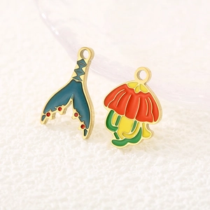 Macro detail of colorful enamel mermaid tail and flower charms made of stainless steel