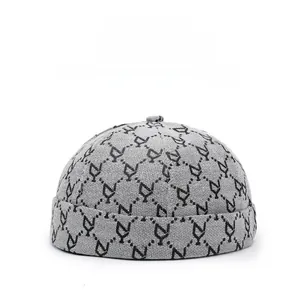 Dettaglio cappello docker grigio con motivo geometrico a lettere Y e trama in maglia fine