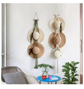 Bohemian macrame hat hangers in green and beige holding straw hats against a white wall