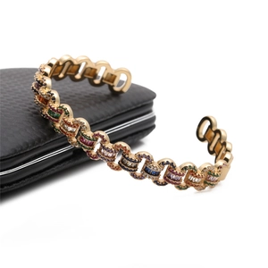Close-up of golden open bangle with colorful crystals on a black leather gift box