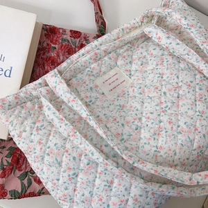 Gros plan du sac fourre-tout en coton matelassé à fleurs avec surpiqûres en losange