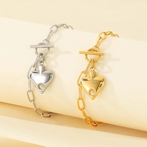 Detail of silver and gold heart pendant necklaces with OT toggle clasps on fabric