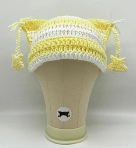 Detail of yellow and white striped knit cat ear hat with star fringe and woven texture