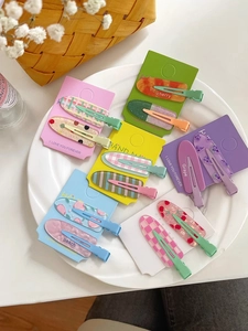 Detail of candy-colored Korean hair clips set in a ceramic plate with fruit patterns