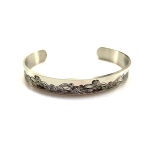 Detailed view of the wave patterns engraved on a 10mm stainless steel cuff bracelet