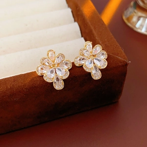 Sparkling zircon flower studs in gold finish displayed on a brown velvet jewelry box