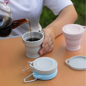 Portable silicone folding travel cups in gray, pink, and blue with metal carabiners