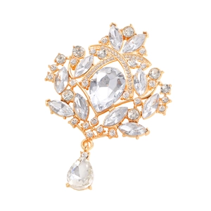 Detail view of a vintage golden brooch with sparkling crystals and a teardrop pendant