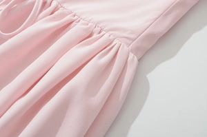 Detail of pink woven fabric dress with sophisticated ruched design and smooth texture