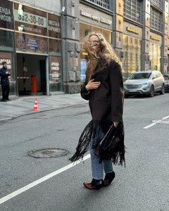 Detail of long fringe tassels on a dark brown wool coat during an urban street walk