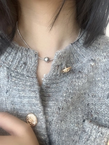 Close-up of minimalist stainless steel silver bead necklace worn with a knit cardigan