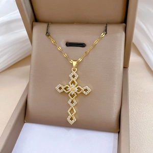 Detail of cross pendant necklace with white zircons on a gold-plated fishbone chain