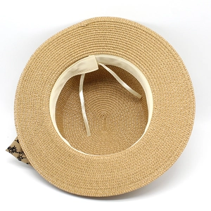 Detail of wide brim straw hat interior showing adjustable drawstring and floral ribbon