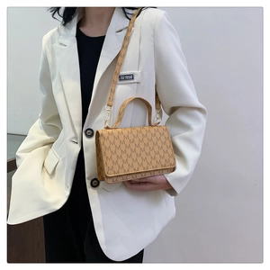 Detailed view of brown letter M monogram crossbody bag with golden metal hardware