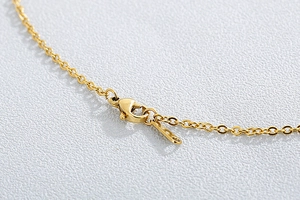 Detail of gold metal O-chain necklace with a secure lobster clasp closure on white surface