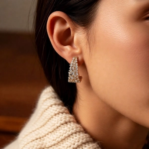 Gros plan d'un mannequin portant des boucles d'oreilles en C plaqué or 18 carats et zircons