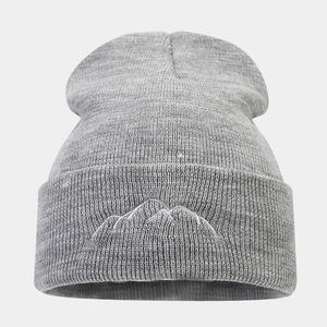 Close-up of grey knitted beanie featuring detailed mountain peak embroidery on the cuff