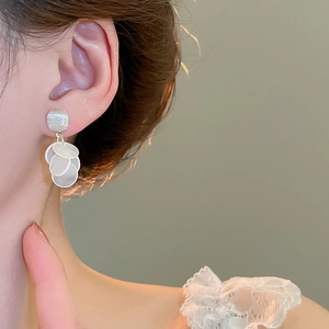 Close-up of layered shell pendant earrings with golden accents on a female model
