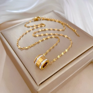 Macro shot of gold cylinder pendant with zircon inlay and Roman numeral details