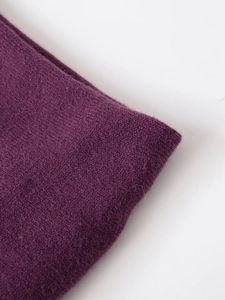 Close-up of dark purple knit fabric showing fine texture and soft wool blend material