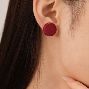 Macro shot of elegant burgundy silk round stud earring worn on model's earlobe