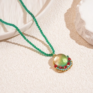 Detail of bohemian green faceted glass beads and gold-trimmed resin pendant on necklace