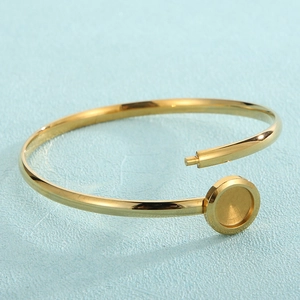Detailed view of golden open cuff bracelet with circular mount and polished finish