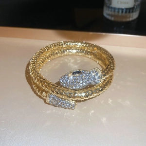 Close-up of golden snake bangle with crystal pavé details on head and tail