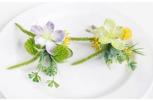 Detail of purple and green artificial wedding corsages on a white plate