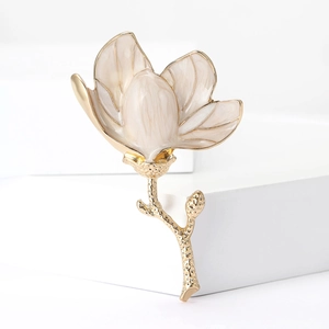 Macro detail of enamel magnolia flower brooch with textured gold alloy stem
