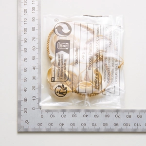 Bohemian seashell and pearl anklet measurement shown with a metal ruler in packaging