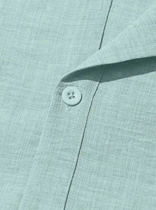 Close-up of Cuban collar and matte button on light teal linen texture casual shirt