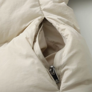 Close-up of the beige quilted jacket showing smooth metal zipper pocket and fabric texture